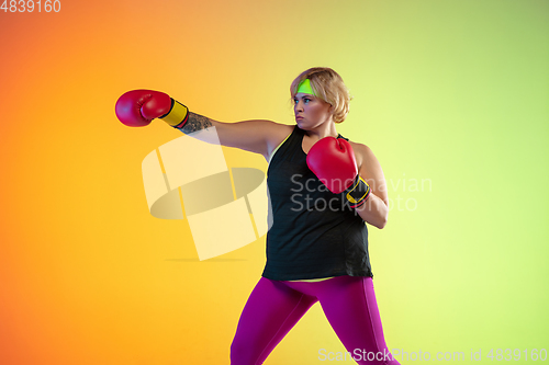 Image of Young caucasian plus size female model\'s training on gradient orange background
