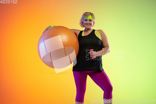 Image of Young caucasian plus size female model\'s training on gradient orange background