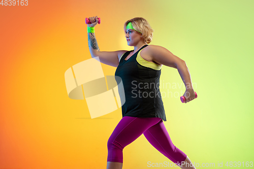 Image of Young caucasian plus size female model\'s training on gradient orange background