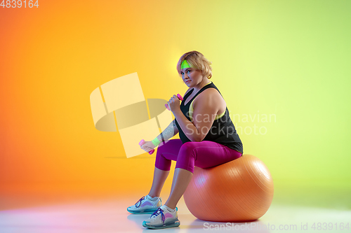 Image of Young caucasian plus size female model\'s training on gradient orange background