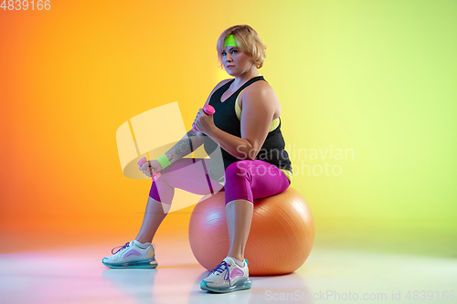 Image of Young caucasian plus size female model\'s training on gradient orange background