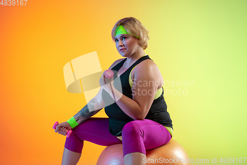 Image of Young caucasian plus size female model\'s training on gradient orange background
