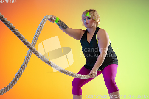 Image of Young caucasian plus size female model\'s training on gradient orange background