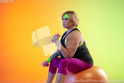 Image of Young caucasian plus size female model\'s training on gradient orange background