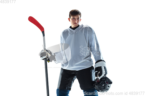 Image of Young male hockey player with the stick on ice court and white background