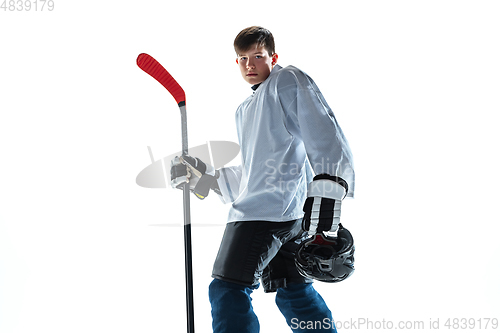 Image of Young male hockey player with the stick on ice court and white background