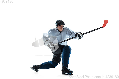 Image of Young male hockey player with the stick on ice court and white background