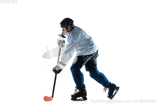 Image of Young male hockey player with the stick on ice court and white background