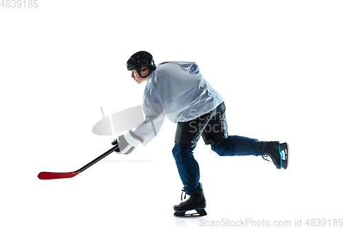 Image of Young male hockey player with the stick on ice court and white background