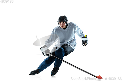 Image of Young male hockey player with the stick on ice court and white background