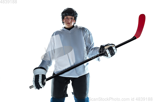 Image of Young male hockey player with the stick on ice court and white background