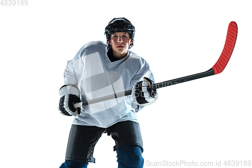 Image of Young male hockey player with the stick on ice court and white background