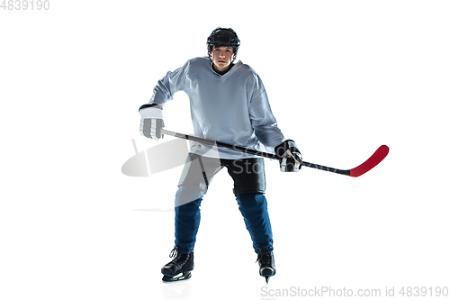 Image of Young male hockey player with the stick on ice court and white background