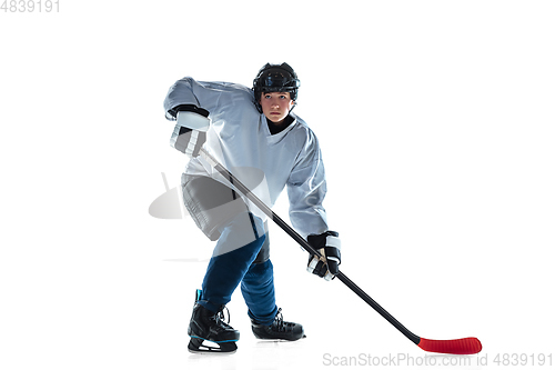 Image of Young male hockey player with the stick on ice court and white background