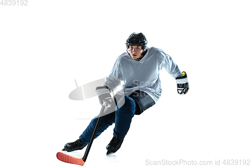 Image of Young male hockey player with the stick on ice court and white background