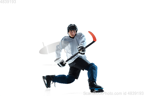 Image of Young male hockey player with the stick on ice court and white background