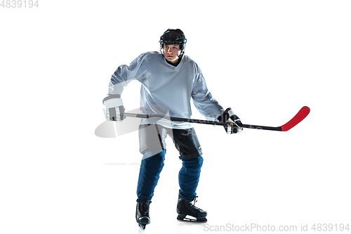 Image of Young male hockey player with the stick on ice court and white background