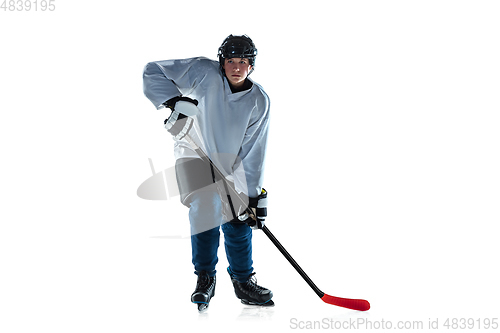 Image of Young male hockey player with the stick on ice court and white background