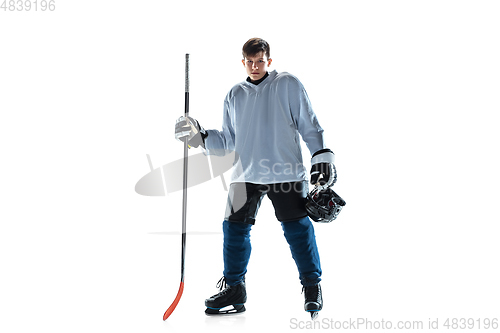 Image of Young male hockey player with the stick on ice court and white background