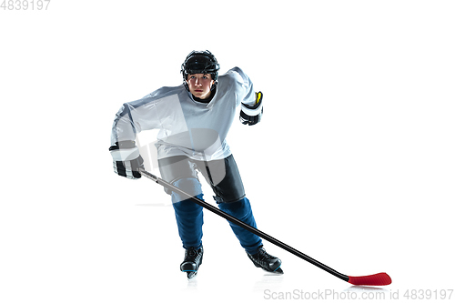 Image of Young male hockey player with the stick on ice court and white background