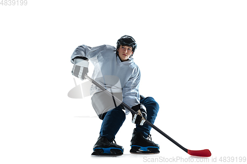 Image of Young male hockey player with the stick on ice court and white background