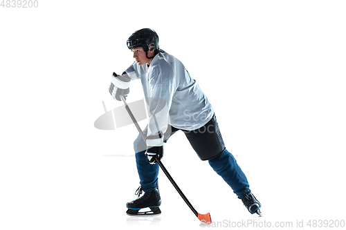 Image of Young male hockey player with the stick on ice court and white background