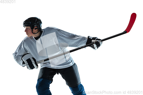 Image of Young male hockey player with the stick on ice court and white background