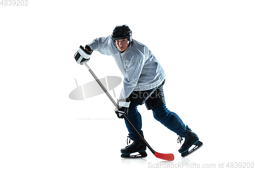 Image of Young male hockey player with the stick on ice court and white background