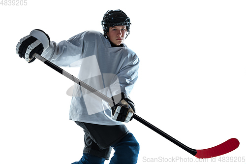 Image of Young male hockey player with the stick on ice court and white background