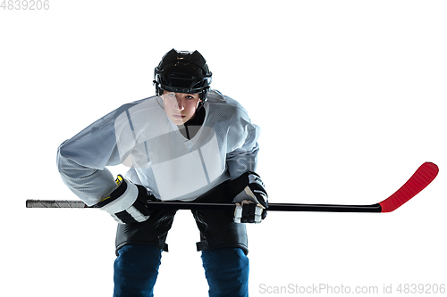 Image of Young male hockey player with the stick on ice court and white background