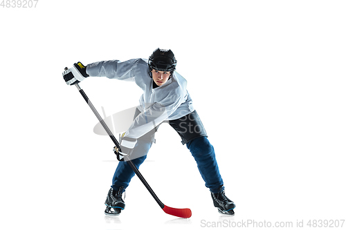 Image of Young male hockey player with the stick on ice court and white background