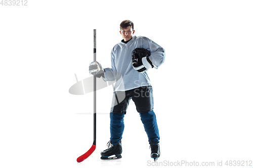 Image of Young male hockey player with the stick on ice court and white background