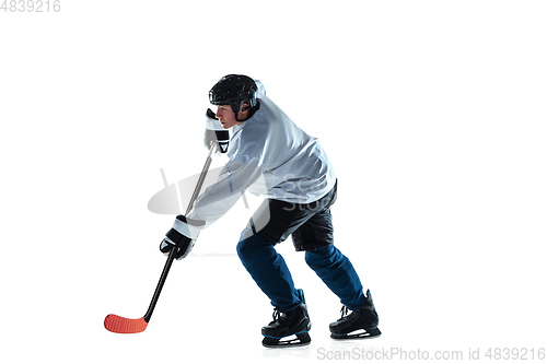 Image of Young male hockey player with the stick on ice court and white background