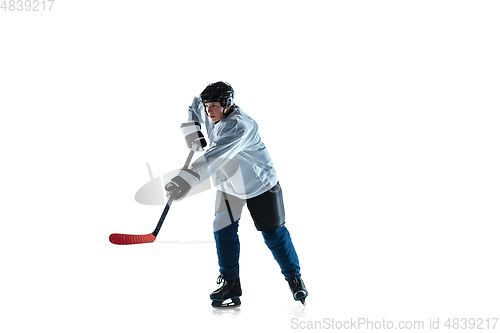 Image of Young male hockey player with the stick on ice court and white background