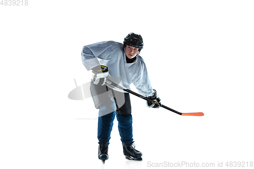 Image of Young male hockey player with the stick on ice court and white background