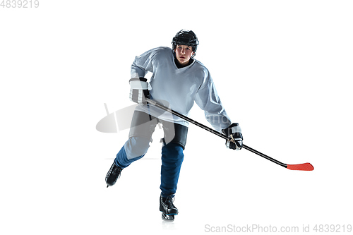 Image of Young male hockey player with the stick on ice court and white background