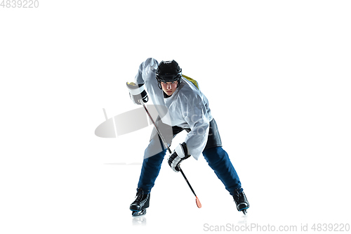 Image of Young male hockey player with the stick on ice court and white background