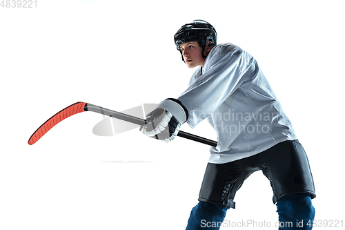 Image of Young male hockey player with the stick on ice court and white background