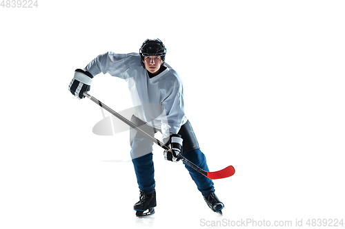 Image of Young male hockey player with the stick on ice court and white background