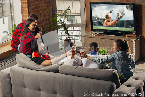 Image of Excited group of people watching sport match at home