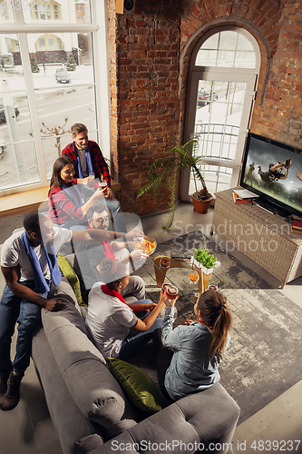 Image of Excited group of people watching sport match at home