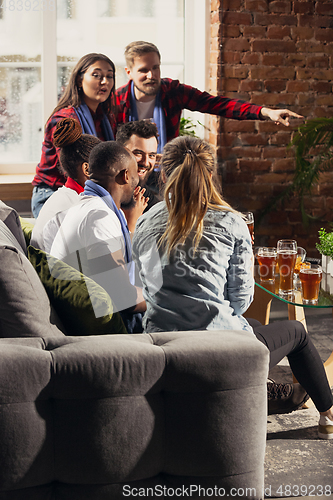 Image of Excited group of people watching football, sport match at home