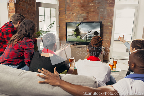 Image of Excited group of people watching sport match at home