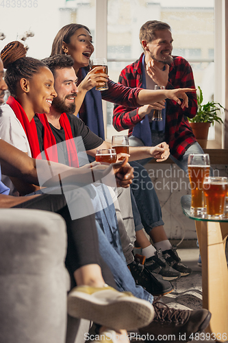 Image of Excited group of people watching football, sport match at home
