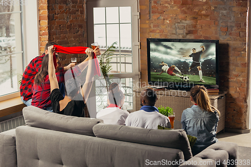 Image of Excited group of people watching sport match at home