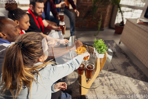 Image of Excited group of people watching football, sport match at home