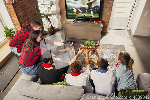 Image of Excited group of people watching sport match at home