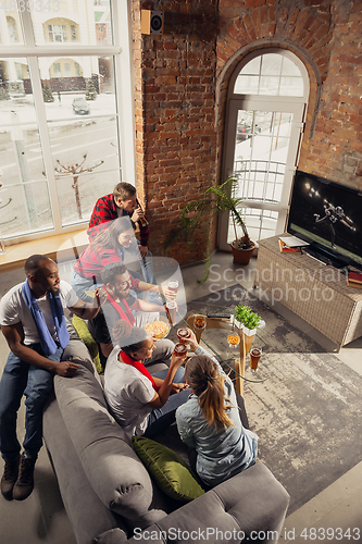 Image of Excited group of people watching sport match at home