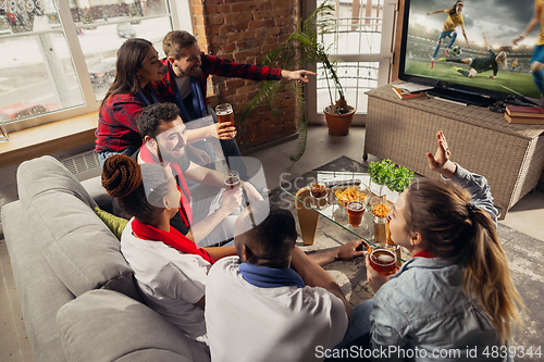 Image of Excited group of people watching sport match at home