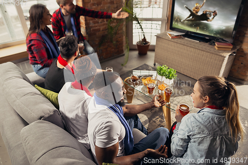 Image of Excited group of people watching sport match at home